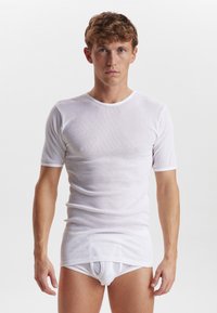 Hvid ribbet t-shirt, korte ærmer, rund halsudskæring, tætsiddende design. Glat tekstur, parret med en hvid boksershorts under. Minimalistisk stil.