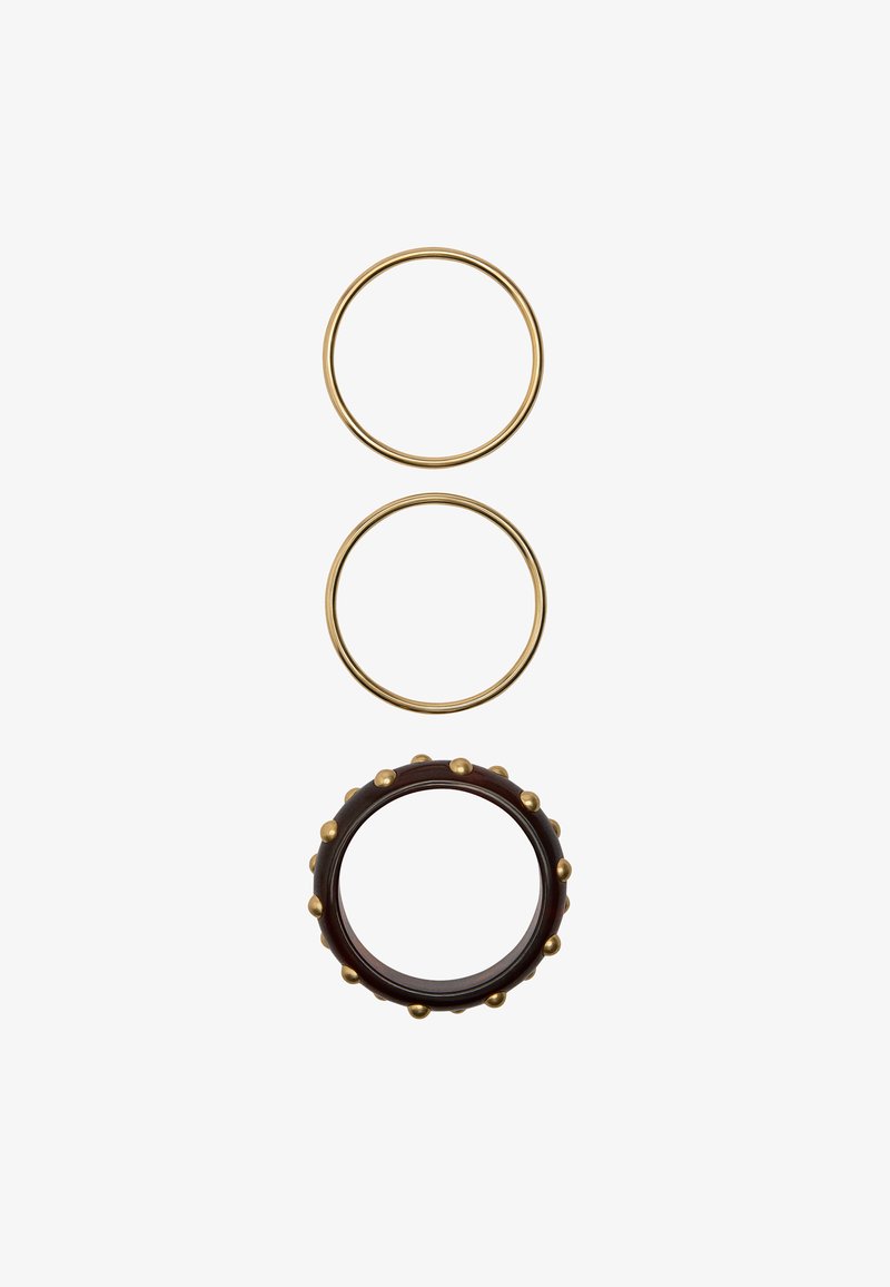 Dwie cienkie złote kolczyki w kształcie kół oraz jeden ciemnobrązowy pierścionek z równomiernie rozmieszczonymi złotymi ćwiekami ułożonymi pionowo na białym tle.