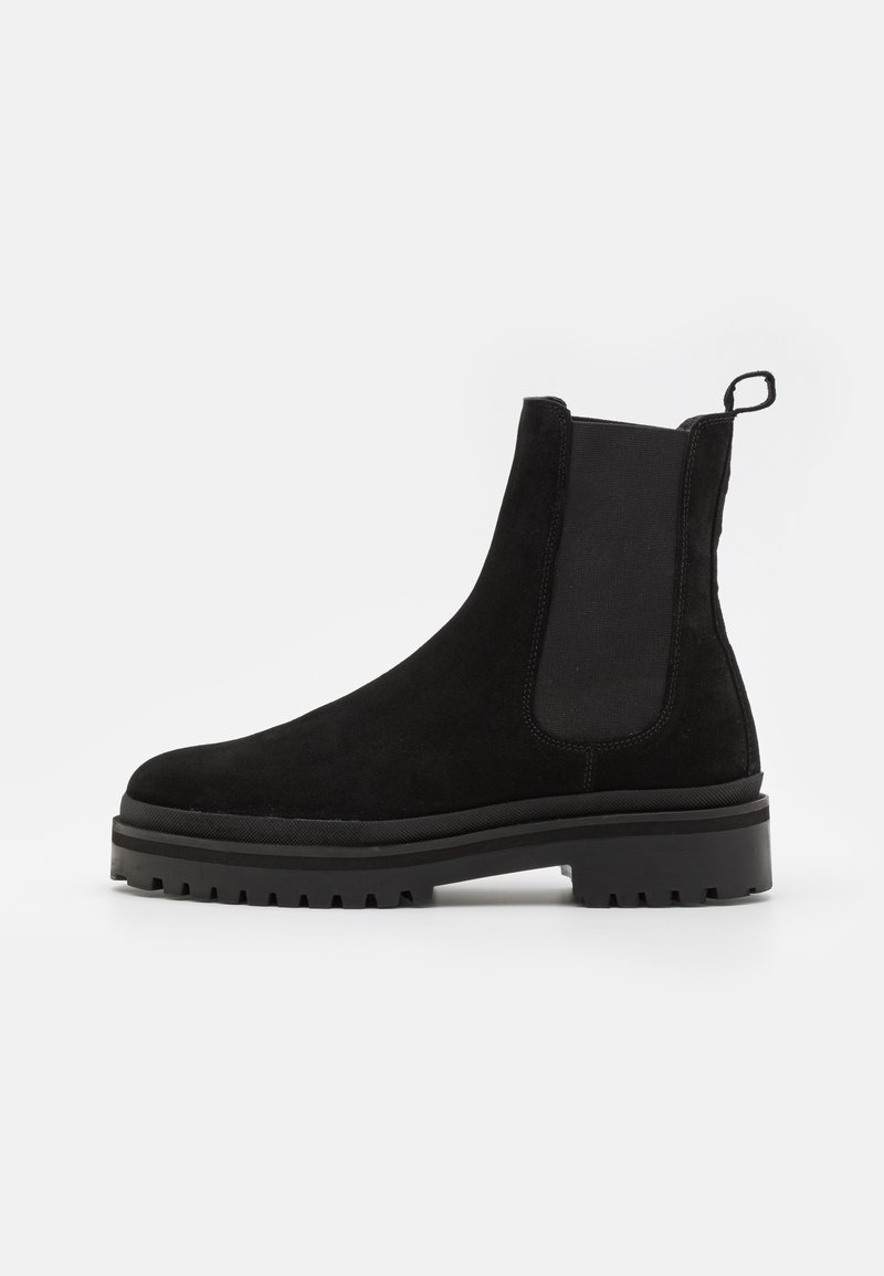 Bottines Chelsea en suede noir avec panneau latéral élastique, languette au talon et semelle en caoutchouc épaisse à motif.