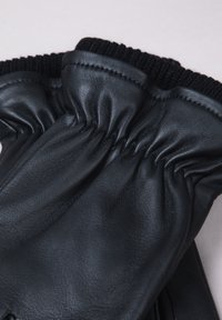 Black leather gloves with gathered wrist, smooth texture, and contrasting black knit cuff. Stitch detailing is visible on the leather.