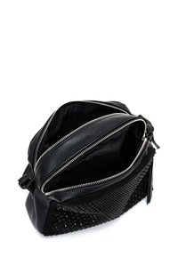 Borsa in pelle nera con tessuto testurizzato e borchie. Due scomparti con zip, tracolla regolabile e rivestimento interno morbido.