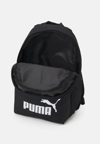 Zaino nero con finitura in tessuto liscio, scomparto principale con zip e tasca frontale che mostra il logo Puma bianco. Inclusi taschini laterali in rete.