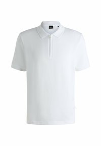 White polo shirt made of ribbed fabric. Features a zippered collar, short sleeves, and a tag on the side. Simple, modern design.