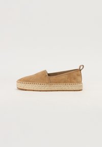 Barna velúr espadrille slip-on cipő, fonott juta talppal. Kerek orrú, hátul kis hurkos dizájnnal, ami megkönnyíti a felhúzást.