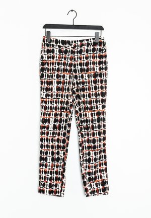 Pantalon à motifs en noir, blanc et rouge avec un design géométrique. Confectionné dans un tissu léger, il présente une coupe slim et une longueur cheville.
