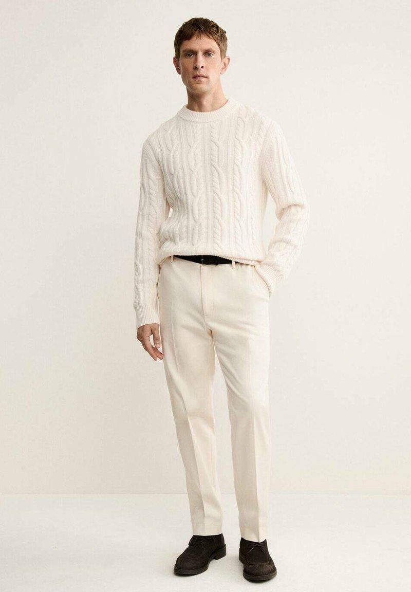 Knit cream sweater with cable design, paired with cream trousers and dark shoes. The outfit features a standard fit and subtle texture.