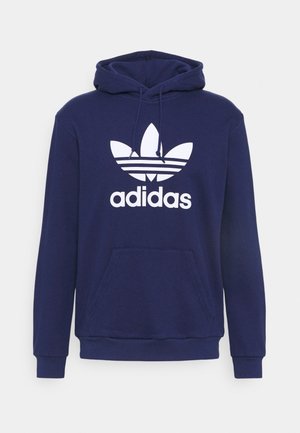 Sudadera con capucha azul marino con bolsillo canguro frontal, capucha ajustable con cordón y gran logotipo blanco de Adidas trefoil centrado en el pecho.