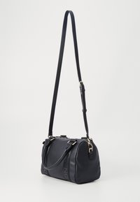 Black leather handbag with textured finish, dual top handles, adjustable shoulder strap, and gold hardware accents. Zipper closure at top.