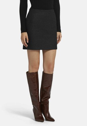 Grijze wollen mini-jurk, gecombineerd met glanzende bruine laarzen tot de knie, met krokodillenleer-embossing en spitse neuzen. Geribbeld zwart longsleeve top.