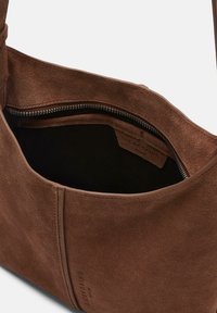 Br�ązowa torebka ze zamszu z zamknięciem na zamek błyskawiczny wewnątrz, o gładkiej fakturze i subtelnym logo na zewnątrz.