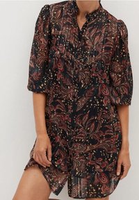 Vestido negro transparente con coloridos patrones florales y de paisley, mangas abullonadas y un cuello alto. Presenta detalles de botones y plisados.