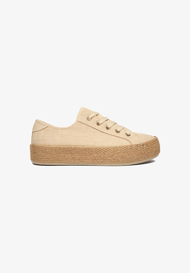Zapatilla baja de lona beige con suela plataforma gruesa de yute tejido y cordones beige, mostrada de lado sobre un fondo blanco.