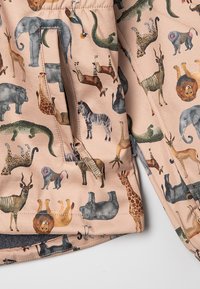 Tiermuster-Jacke mit beigem Hintergrund, die verschiedene illustrierte Tiere zeigt, mit Reißverschlusstasche und weichem Stoffgefühl.