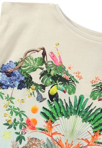 Camicia a maniche corte di un leggero beige con una vivace stampa tropicale che presenta un tucano, un leopardo, fiori e diverse foglie in verde e accenti colorati.