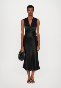 Rochie midi din satin negru, cu decolteu adânc în V, corp ajustat cu detalii plisate și margine evazată. Accesorizată cu o geantă de mână rotundă negre.