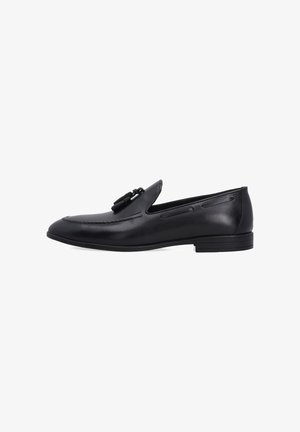 Zwarte leren loafers met een ronde neus, minimale stiksels en een decoratieve franjes. De zool is plat met een subtiele hak.