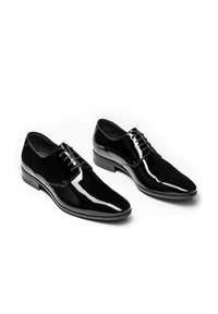 Scarpe eleganti in pelle nera lucida con punte affusolate, dettagli con lacci e una finitura liscia. Presentano un tacco basso e impilato.
