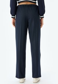Navyblauwe hoge taillebroek met een elastische tailleband, een gladde textuur en een rechte pijpdesign, met minimale details en zonder zakken.