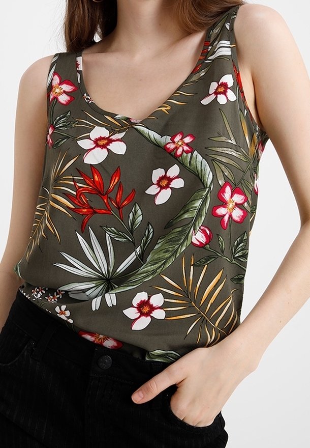 Zielony top bez rękawów z kwiatowym wzorem, mający dekolt w kształcie litery V, kolorowe tropikalne wzory i lekką tkaninę, zestawiony z czarnymi spodniami.
