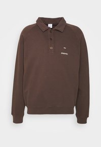 Pullover marrone con colletto, pattina abbottonata e maniche lunghe raglan. Presenta un logo in testo bianco sul petto e un tessuto testurizzato.