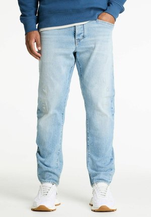 Lichtblauwe denim jeans met een relaxte pasvorm, voorzien van verwerkte details en een klassieke vijf-pocket stijl. Draagt bij witte sneakers.