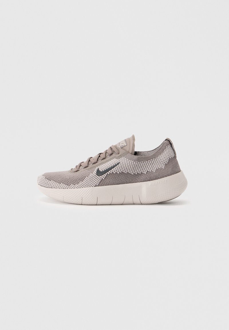 Nike sneakers har en letvægtstrik overdel i dæmpet beige med et tekstureret mønster, mørkegrå logo og en fleksibel, polstret hvid sål.
