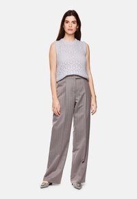 Light blue knitted sleeveless top with diamond pattern, paired with high-waisted gray pinstripe trousers and gray shoes with detailing.