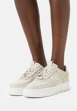 Jasno-beżowe sneakersy z gładką skórzaną cholewką, białą gumową podeszwą i tonowymi sznurówkami. Wyróżniają się subtelnym logo i teksturowanymi detalami na podeszwie.