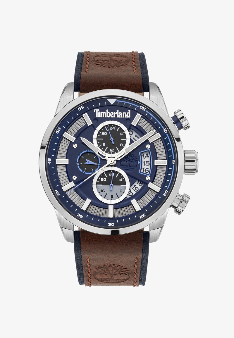 Timberland hronogrāfa pulksteņi ar nerūsējošā tērauda korpusu, zilu ciparnīcu, brūnu ādas siksniņu un sudraba akcentiem. Tam ir trīs subciparnīcas.