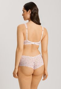 Valkoinennauha-alusvaatesetti vaaleanpunaisena, jossa on kukkakuosi, säädettävät olkaimet, hakasuljenta takana ja erottuvat reunat.