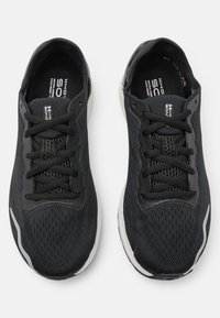 Zwarte sportieve sneakers met een bovenwerk van mesh, vetersluiting en een witte zool. Heeft subtiele grijze accenten en een textuurpatroon aan de zijkanten.