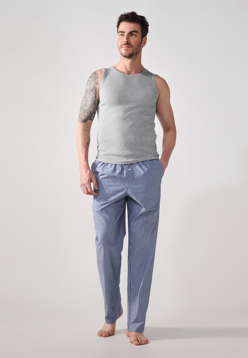 Débardeur gris sans manches associé à un pantalon de pyjama rayé bleu et blanc. Tissu léger, coupe décontractée et texture douce.