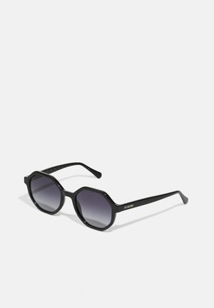 Black octagonal sunglasses with gradient dark gray lenses. Features textured black temple arms and a gold logo on the side.