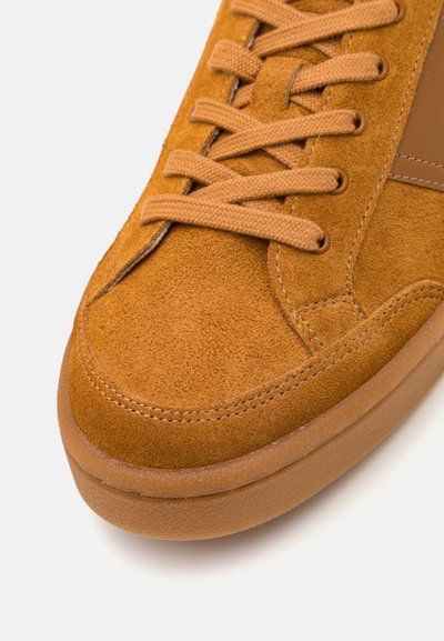 Soëdkingad soojades pruunides toonides, millel on tekstuuriga pind, lameed nöörid ja ümardatud kummitald. Lihtne disain peente õmblusdetailidega.