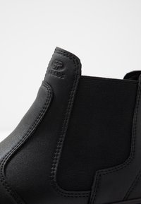 Stivale Chelsea nero in pelle, dotato di pannelli laterali elasticizzati e cuciture visibili. Logo impresso alla caviglia. Texture liscia.