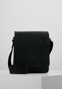Borsa a tracolla in pelle nera con design piatto, tracolla regolabile e superficie testurizzata con un discreto patch con logo.