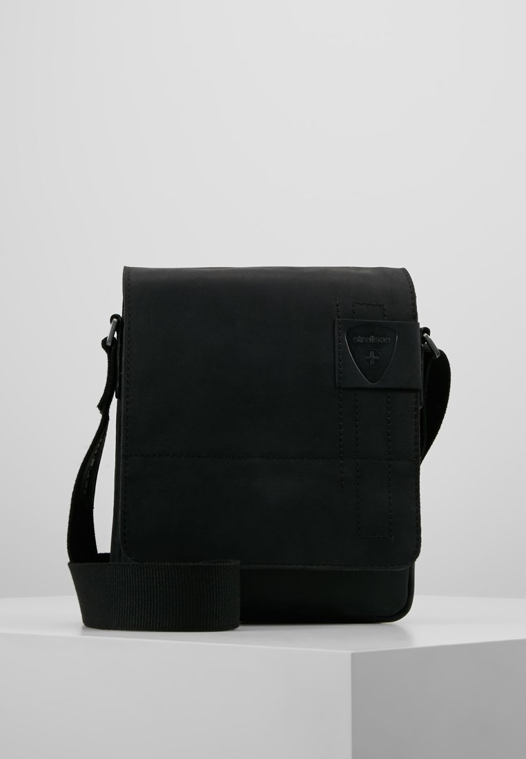 Borsa a tracolla in pelle nera con design piatto, tracolla regolabile e superficie testurizzata con un discreto patch con logo.