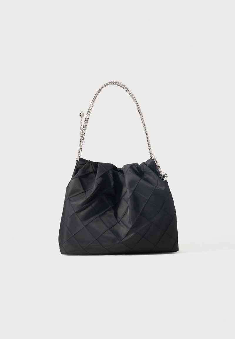 Μαύρη καπιτονέ τσάντα με ασημένιο αλυσίδωτο λουρί, μαλακό, χαλαρό σώμα και ραφές με μοτίβο διαμαντιού σε απλό φόντο.