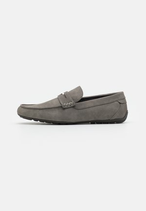 Mocassins en daim gris avec une semelle en caoutchouc plate, design à enfiler, et couture sur le devant et sur les côtés.
