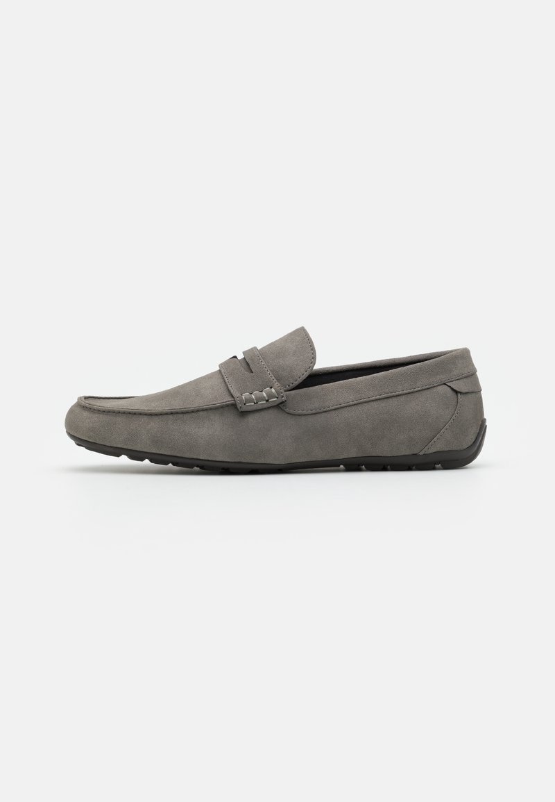 Mocassins en daim gris avec une semelle en caoutchouc plate, design à enfiler, et couture sur le devant et sur les côtés.