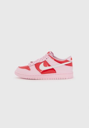 Baskets basses Nike rose et rouge avec logo swoosh blanc, fermeture à lacets et semelle en caoutchouc, vues de côté sur fond uni.