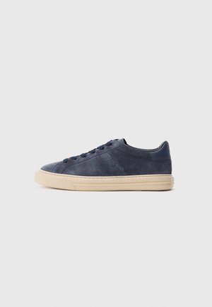 Navy blue suede low-top sneaker with tonal laces, beige rubber sole, and stitched design on the side, shown in profile.