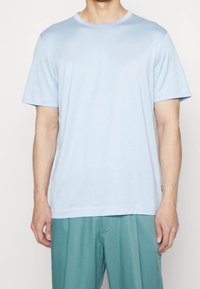 Světle modré tričko s krátkým rukávem a kulatým výstřihem, vyrobené z měkké tkaniny, s uvolněným střihem a rovným lemem.