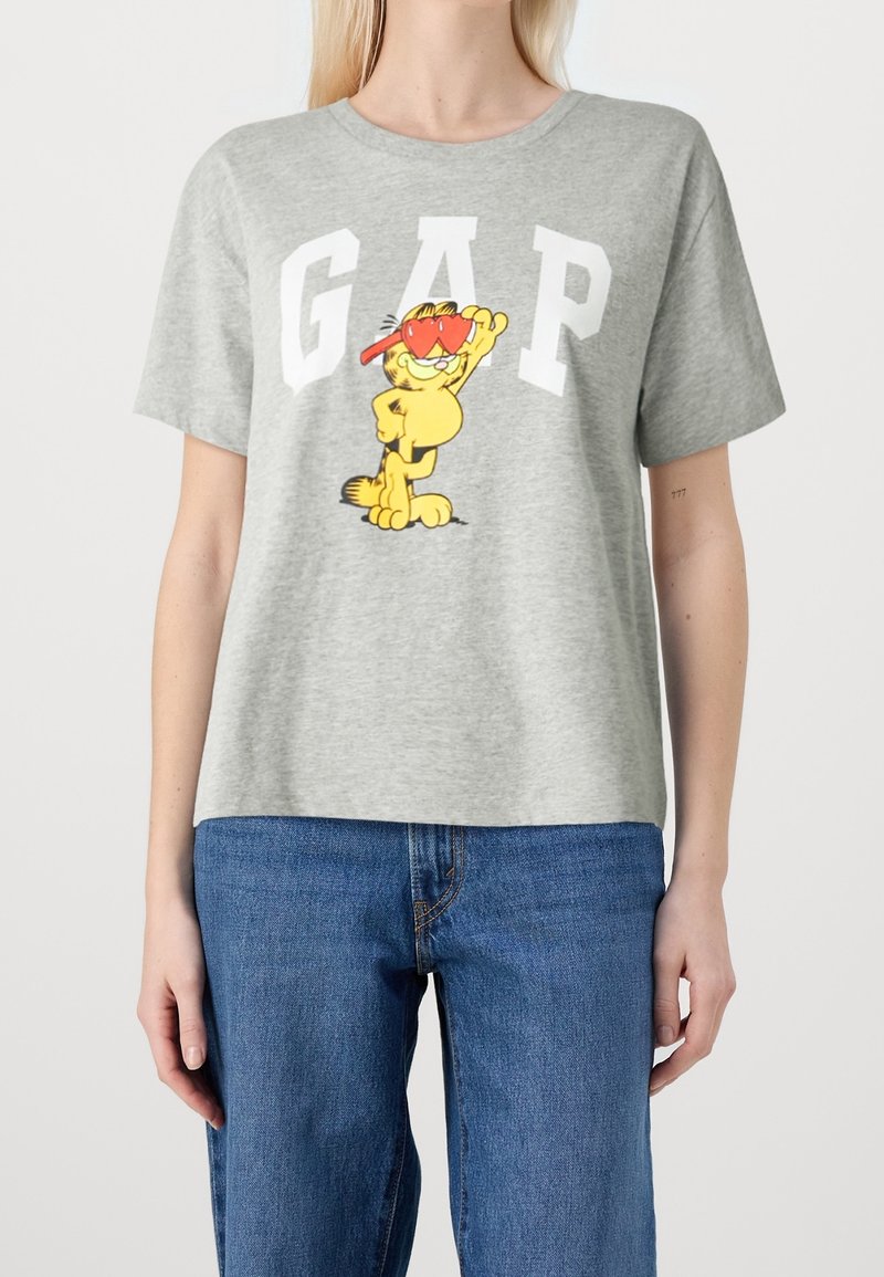 Camiseta de algodón gris claro con un gráfico de un gato de dibujos animados colorido y el texto "GAP" en letras blancas en negrita en el frente.