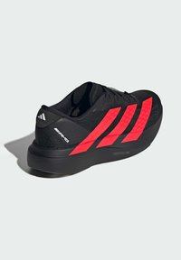 Black athletic shoe with red striped accents, synthetic upper, textured design, and thick black sole labeled "LIGHTSTRIKE PRO."