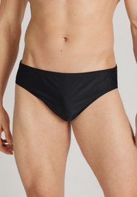 Sorte svømmeboksere lavet af glat, let materiale med et lavtaljesnit. Har minimal syning og en diskret logopynt.