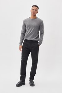 Pulover gri cu mânecă lungă, asortat cu pantaloni negri. Puloverul are gât rotund; pantalonii au închidere cu buton și buzunare. Pantofi negri.