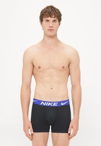 Crne muške bokserice s plavim elastičnim pojasom na kojem se nalazi Nikeov logo. Dizajnirane za prilagodljiv i udoban fit.