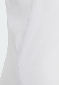 Tissu blanc avec une texture lisse et un léger éclat. Présente des coutures cousues le long des bords, mettant en valeur la forme et le design du vêtement.