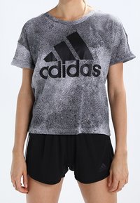 Black and gray patterned T-shirt with short sleeves, featuring a prominent black Adidas logo. Paired with black athletic shorts.